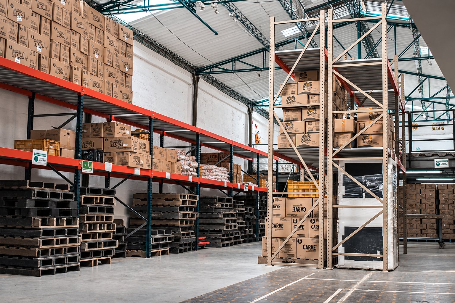 Notre dépôt : rayonnages chargés de cartons et palettes en bois